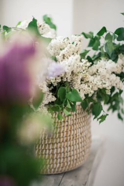 Cam kenarında bir hasır sepet beyaz leylak duruyor