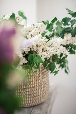 Cam kenarında bir hasır sepet beyaz leylak duruyor