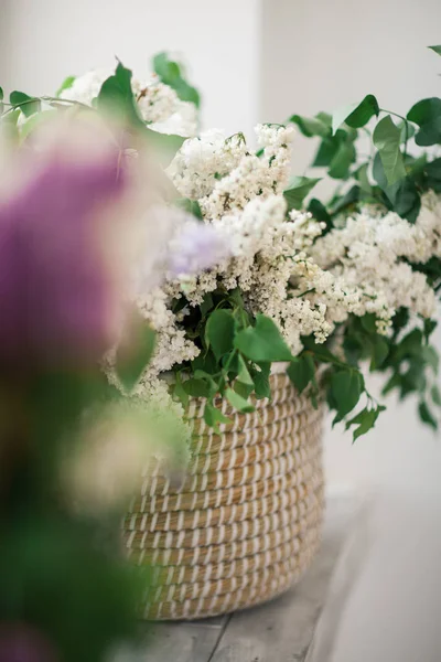 Cam kenarında bir hasır sepet beyaz leylak duruyor