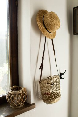 Koridorda evde beyaz bir duvar hasır şapka ve çanta dayan