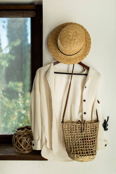 wicker hat and bag hang on a white wall in the hallway at home