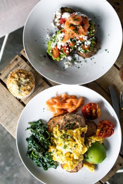 Sağlıklı besleyici kahvaltı fikir: çırpılmış yumurta, somon, ıspanak ve ızgara domates ile avokado tost. Bitkisel kökenli kavramı gıda.