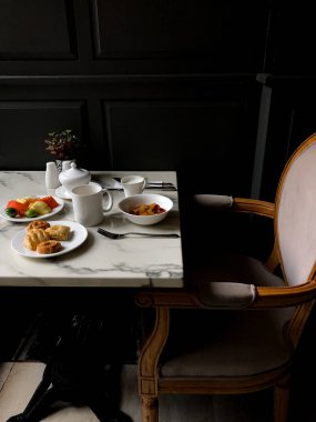 Kahvaltı masası tabak dolusu yiyecek, ekmek, meyve ve kahve lüks otelde mermer masaya servis