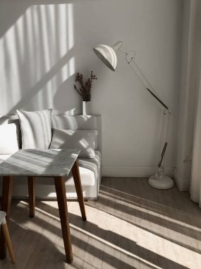 Güneş ışığı ile mermer masa, lamba ve sofa gölgeler içinde parlak oda. Dekor kafe için fikir