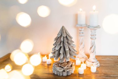 Beyaz ahşap süslenmiş Noel ağacı mumlarla ve altın parlak ışıklar bulanık. Metin için yer. El yapımı şenlikli kavramı