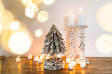 Beyaz ahşap süslenmiş Noel ağacı mumlarla ve altın parlak ışıklar bulanık. Metin için yer. El yapımı şenlikli kavramı