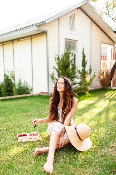 美丽的女孩与长发享受夏天在一个国家的房子和吃草莓 与自然的统一 那女人吸入新鲜空气 女人喜欢生活 — 图库照片