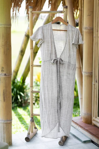 グレーのリネンのドレスは 竹の家の部屋で絞首刑執行人にぶら下がっています 自然なサマードレス 環境コンセプト — ストック写真