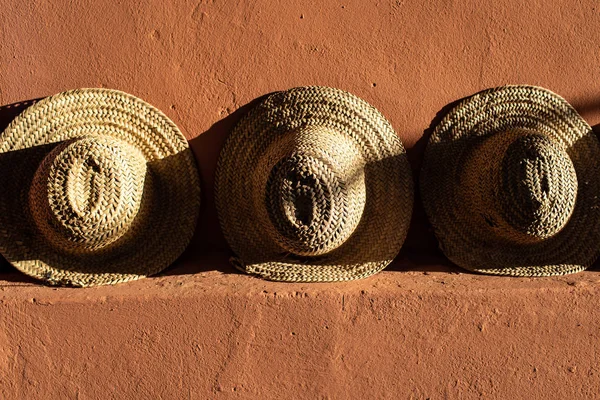 Straw beach hats standing on terracotta  clay wall.  Bright sunl — Stock Photo, Image