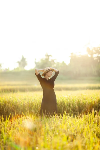 Femme en robe noire et chapeau de paille . — Photo