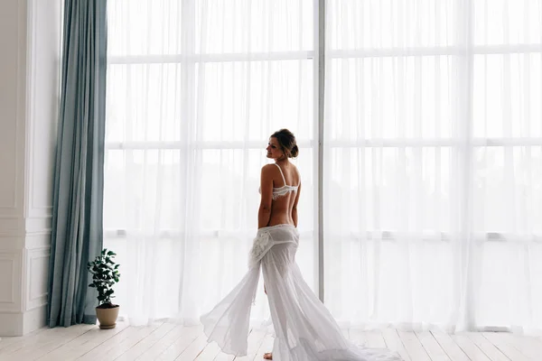 Morning fees of a pretty bride at the window. Brides in a stylish apartment