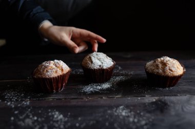 metin için bir yer ile ahşap bir masada krem olmadan cupcake. Bir el cupcakes biri için ulaşır.