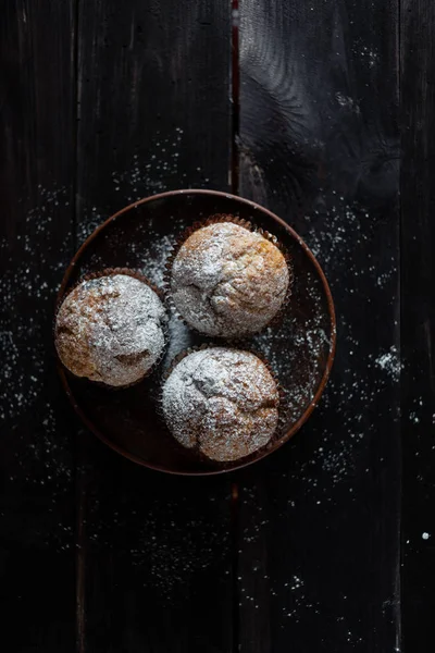 Tre muffin su un tavolo di legno sono cosparsi di zucchero a velo — Foto Stock