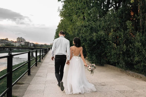 Ευτυχισμένος νύφη και γαμπρός περπατώντας κατά μήκος του περιπάτου την αυγή. Γάμος στο Άμστερνταμ — Φωτογραφία Αρχείου