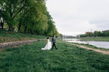 Gelin ve damat sokakta yürüyor. Nehir kıyısı, temiz hava
