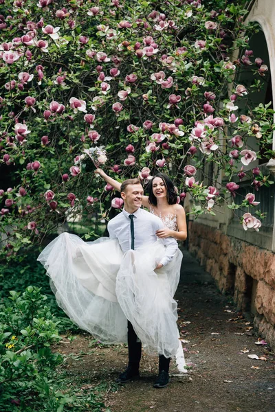 Loving couple fooling around each other near a tree with blooming magnolia — Stock Photo, Image