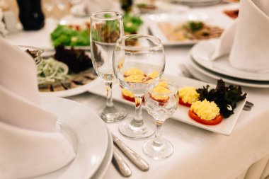 beyaz bir masa örtüsü üzerinde üç şarap kadehi vardır