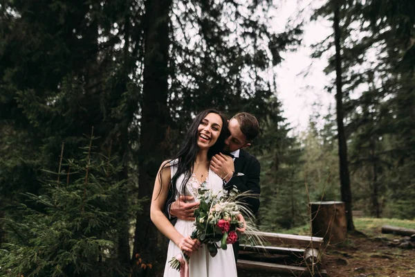Stijlvolle paar bruid en bruidegom gekleed in een trouwjurk en pak van de bruidegom. glimlachend op elkaar — Stockfoto