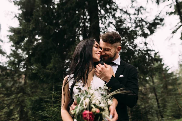 Couple élégant mariée et marié debout dans la forêt et câlin — Photo