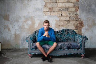 Adam eski kanepede oturuyor. eski çatlak duvar