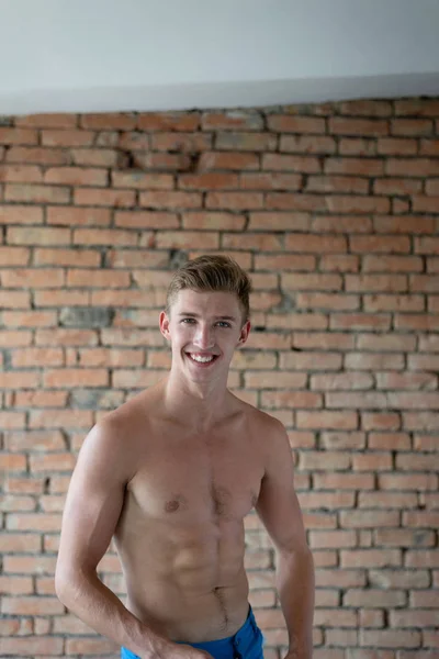 The guy is half naked against a brick wall smiling. — Stock Photo, Image