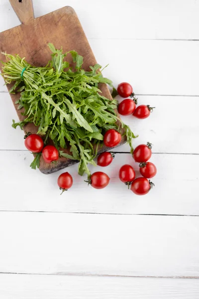 No, na kuchyňském stole jsou liščí rucola, vedle nich je pár malých rajčat — Stock fotografie