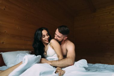 seks öncesi ön sevişme, bir adam ve yatakta bir kadın öpücük. İç çamaşırı giymiş