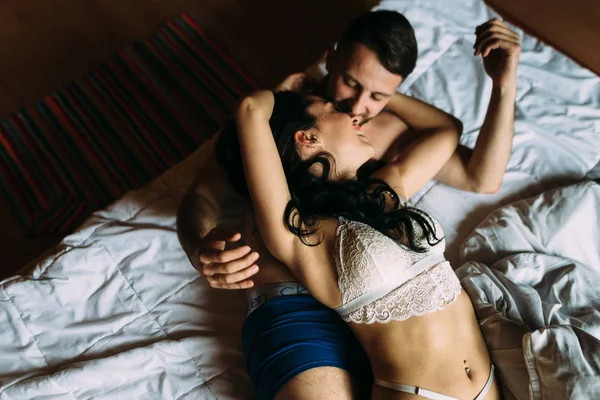 Snygg och passionerad par i sina underkläder kysser på sängen hemma — Stockfoto