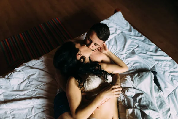 Elegante casal homem e mulher mentira nua na cama e beijo apaixonadamente — Fotografia de Stock