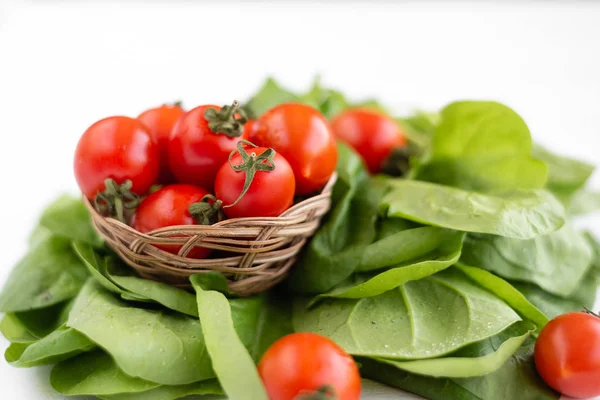 A small wicker basket in it are ripe and juicy cherry tomatoes — Stock Photo, Image