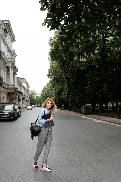 Elegante joven estudiante se para en la calle y disfruta de la vida — Foto de Stock