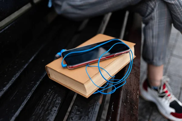 A padon egy barna könyvet, telefonnal és fejhallgatóval. — Stock Fotó
