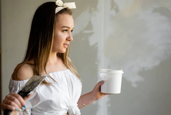 Charming teenager girl holding a putty knife and putty making re — Stock Photo, Image