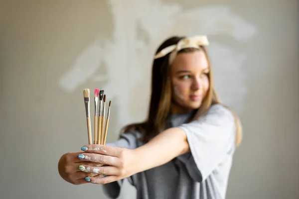 女孩艺术家用画笔在手上绘画的工作 — 图库照片