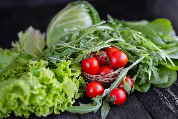 Salade verte fraîche à la roquette, tomates, sur fond sombre — Photo