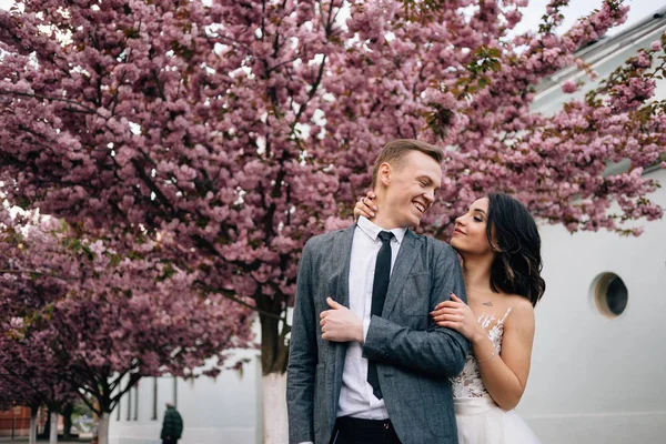 Позитивная молодая пара в свадебной одежде прогуливаясь по парку — стоковое фото