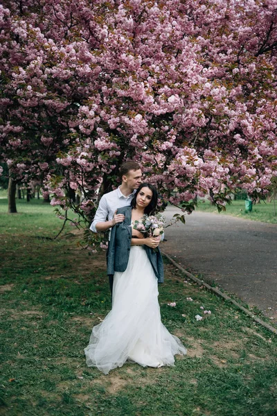 Влюбленная пара фотографируется на фоне цветущих деревьев — стоковое фото