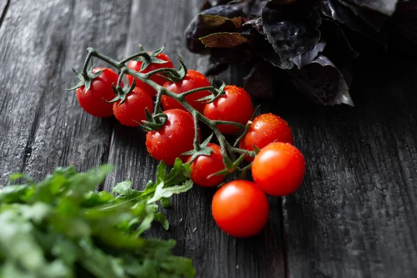 Juicy appetizing cherry tomatoes with basil arugula lie on a vin — Stock Photo, Image