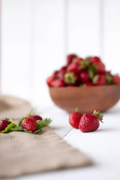 Reife und schmackhafte Beeren liegen auf dem Tisch, grüne Erdbeerblätter und reife Beeren — Stockfoto