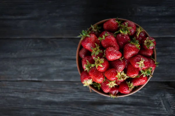 Las fresas maduras yacen sobre una mesa de madera en un plato. Presentado por close-up . — Foto de Stock