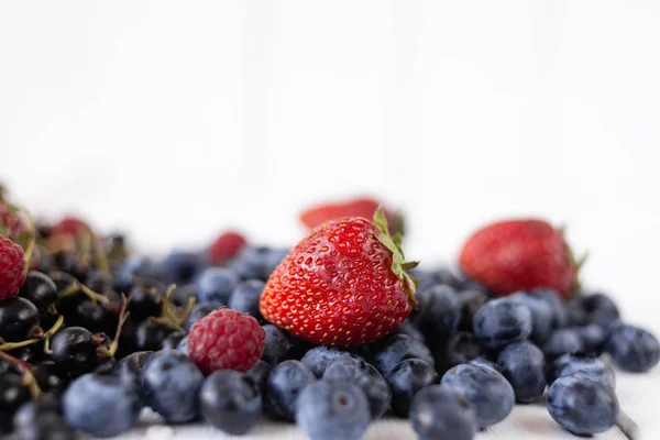 Bayas maduras fresas, arándanos, frambuesas y grosellas en una mesa blanca. Deliciosas bayas de verano — Foto de Stock