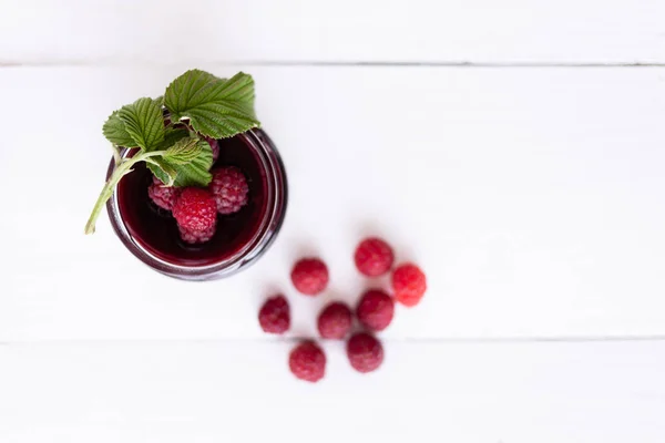 Ripe berries lie on a white table near a jar of jam — Stock Photo, Image