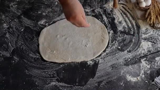 The chef prepares the cake for pizza, on the table is flour and a piece of dough — 비디오