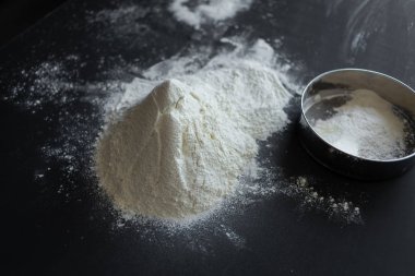 masada beyaz buğday unu, yanında bir elek yatıyor.