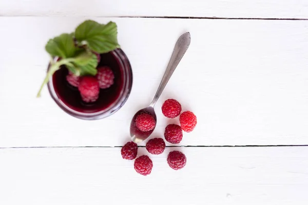 Raspberry jam in a plate, fresh raspberries are lying on a wooden table — Stock Photo, Image