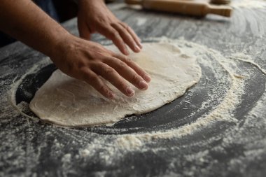 Mutfaktaki şef pizza hamurunu yuvarediyor. Erkek fırıncı eller
