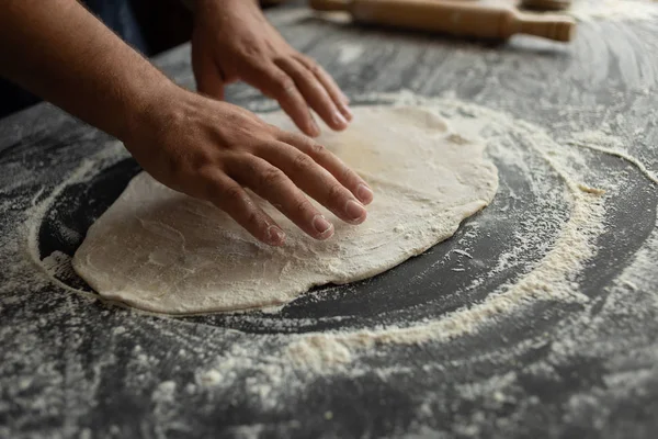 キッチンのシェフがピザ生地をロールアウトします。男性のパン屋の手 — ストック写真