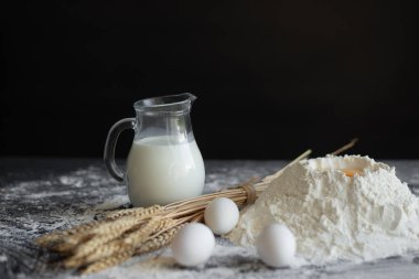 Fırında hamur tarifi malzemeler yumurta, un, süt, koyu bir arka plan üzerinde. Boş metin alanı olan arka plan.