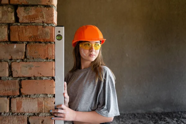 Młody inżynier dziewczyna trzyma poziom pomiaru równomierność ścian. — Zdjęcie stockowe