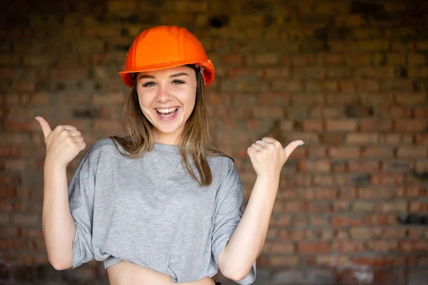 A happy woman is smiling brightly with her arms bent in elbows and showing the thumb top. She is pleased with her work. — Stock Photo, Image
